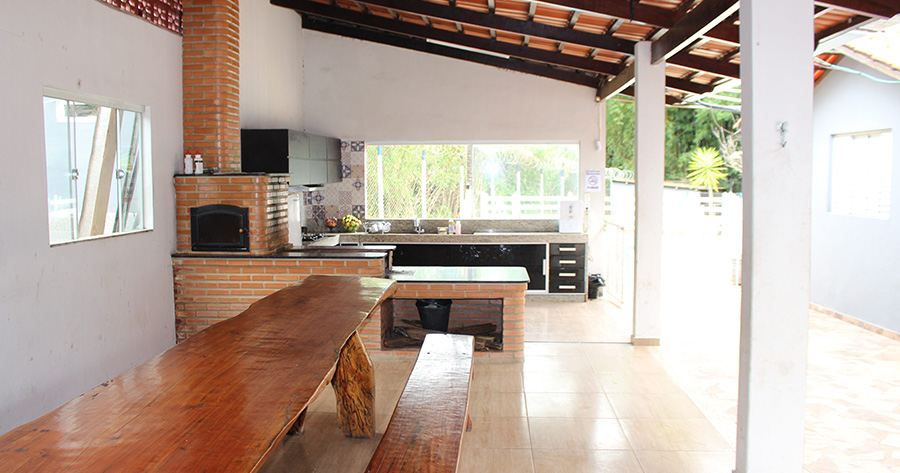 Refeitório com mesa de madeira e cozinha da unidade da Reabilitação BH em Nova Serrana (MG)